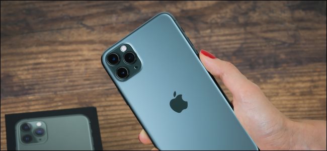 A hand holding an iPhone 11 Max Pro and showing off the back with the camera.